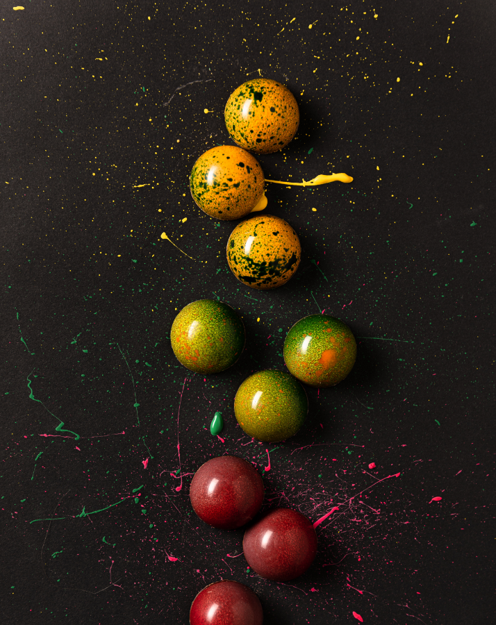 Nobile Schnapspralinen künstlerisch inszeniert mit gelber, grüner, roter Farbe auf dunklem Hintergrund